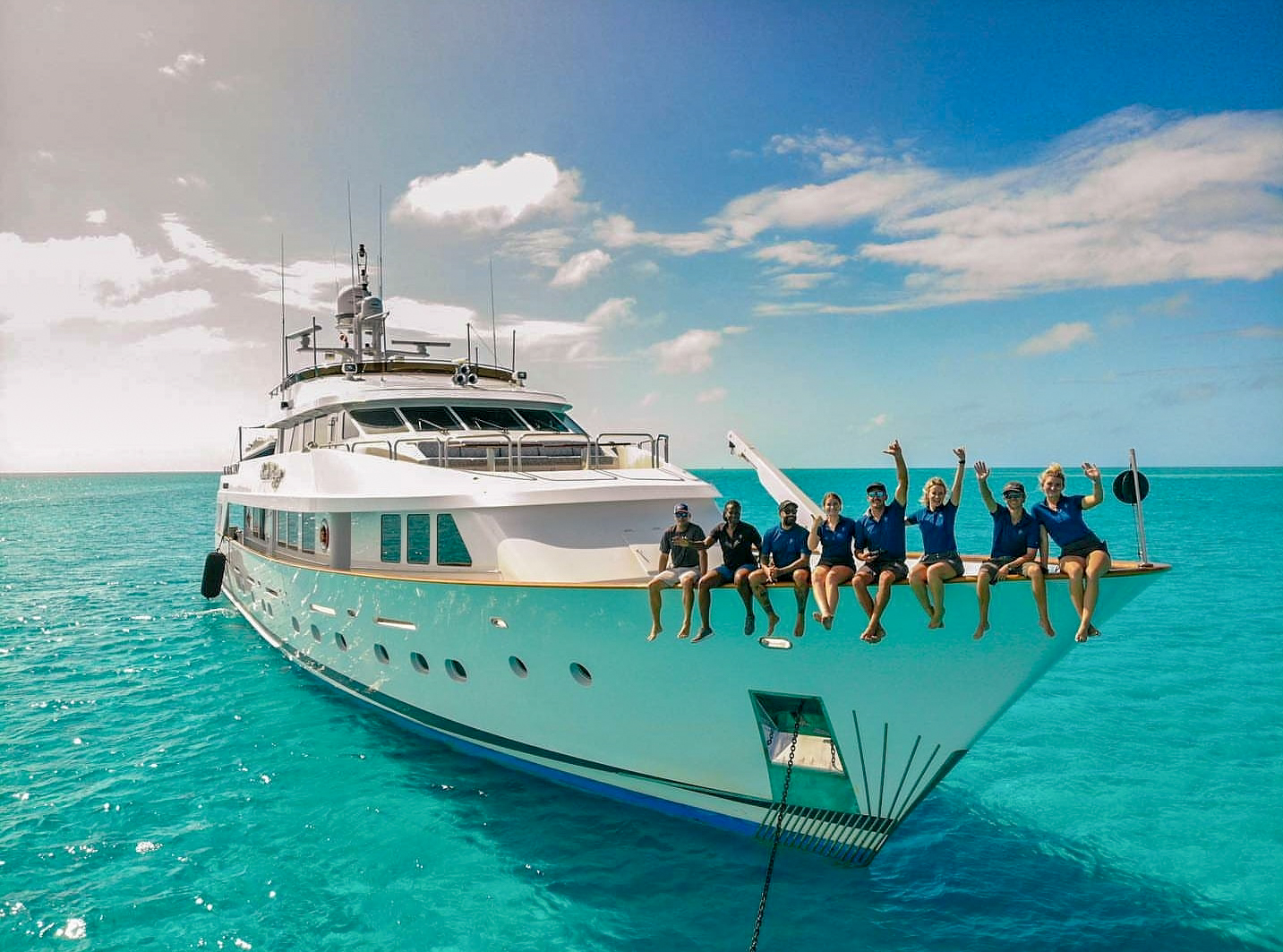 Yacht staff all sitting along edge of boat near the bow